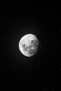 The moon in its gibbous phase, bright white against a deep, black, star-filled sky.